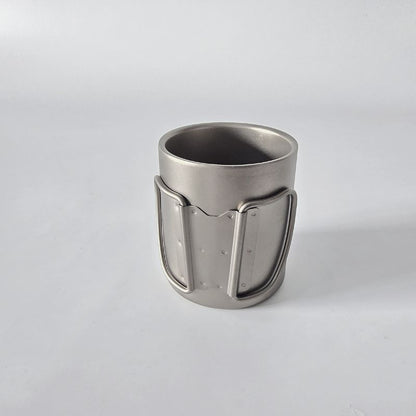 Metallic cup with decorative handle on a light gray background
