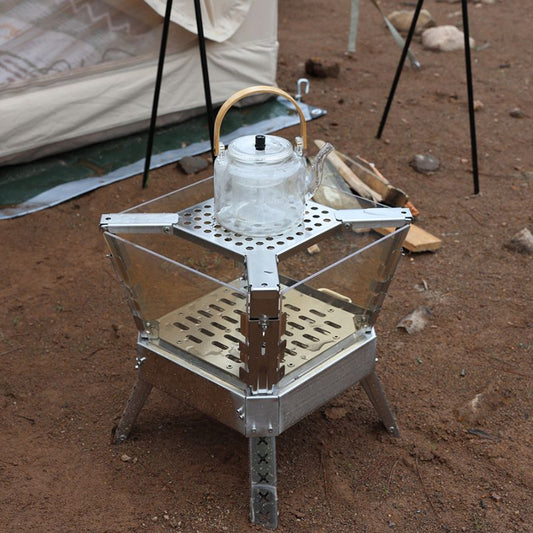 Camping stove with a teapot on a camping site with a tent in the background.