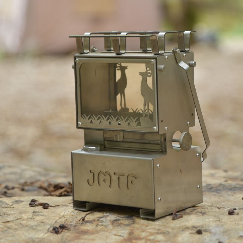 Metallic camping stove with deer design on a natural background