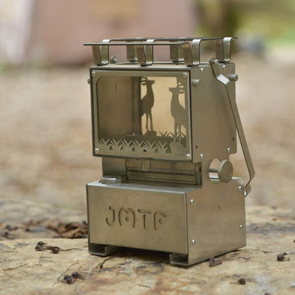 Metallic camping stove with deer design on a natural background