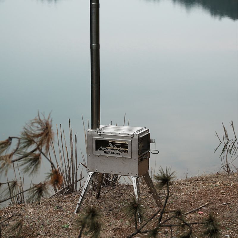 Portable stove on a stand by a body of water with trees in the background