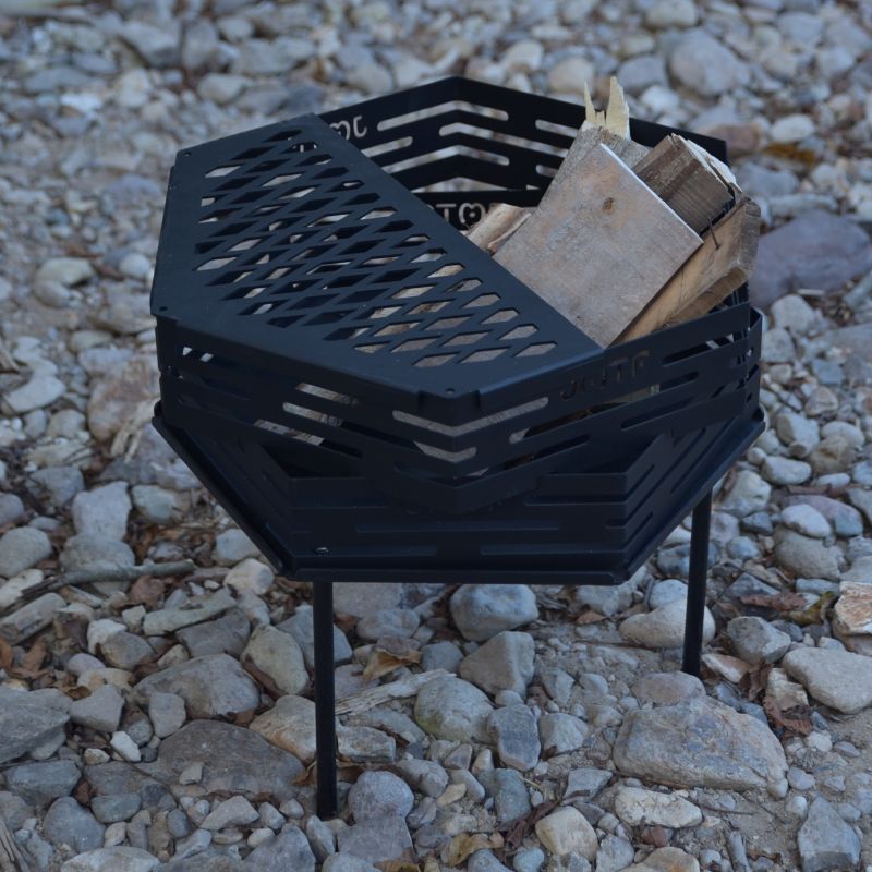 Black metal fire pit with wood on a rocky ground