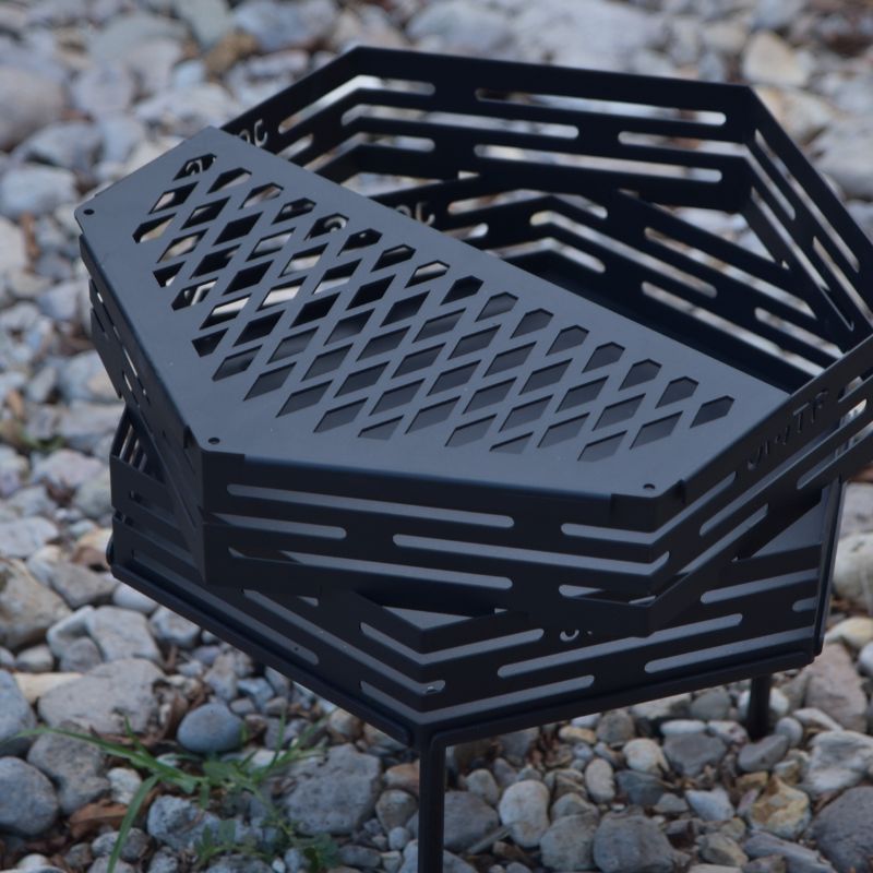 Black metal fire pit basket on a gravel surface