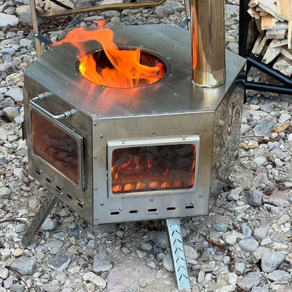 Metallic camping stove with flames on a rocky ground