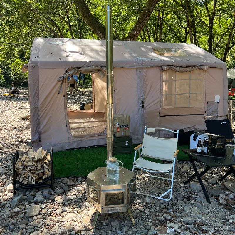 Camping setup with a tent, stove, chair, and table outdoors.