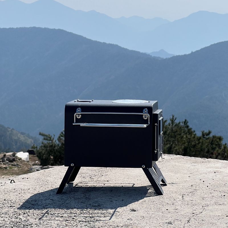 Black portable stove on a mountain top with a scenic view of mountains in the background