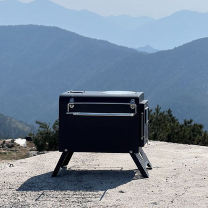Black portable stove on a mountain top with a scenic view of mountains in the background