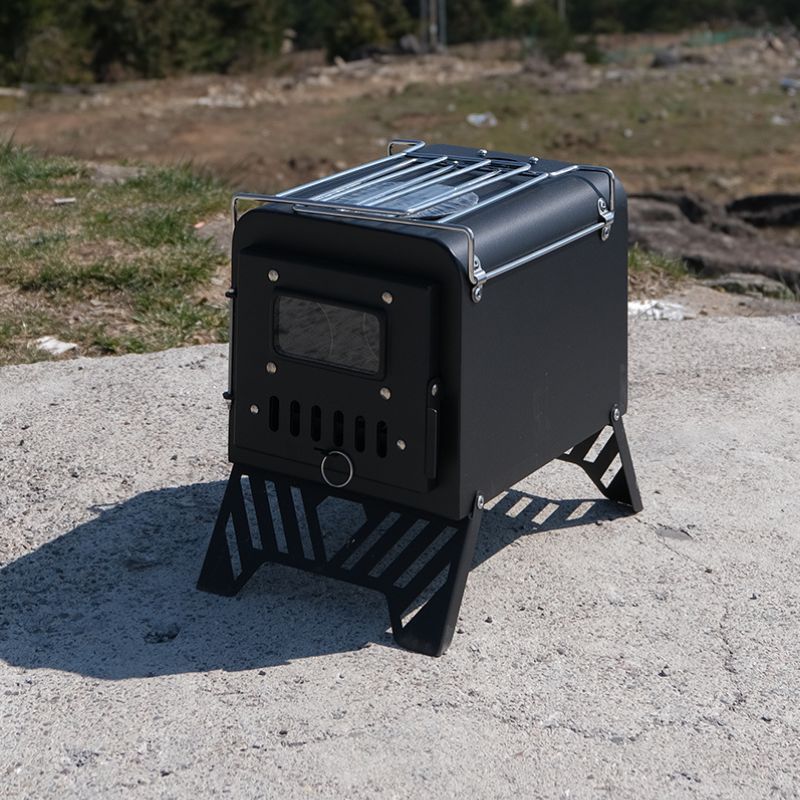 Black portable stove on a concrete surface with grass and trees in the background